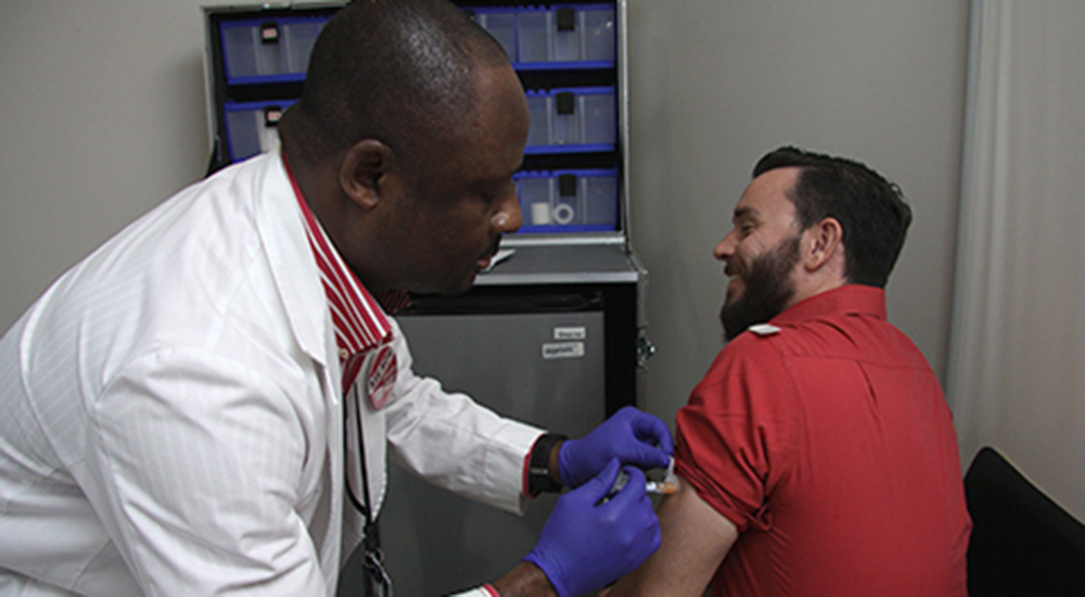 A male nurse gives a man a flu shot