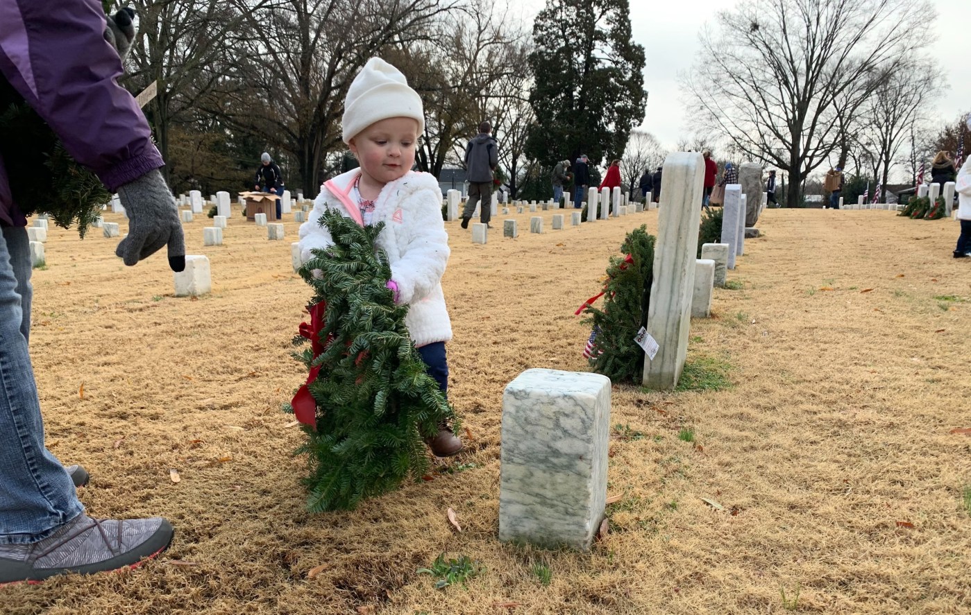 A child places a wreath at Raleigh National Cemetery, North Carolina.