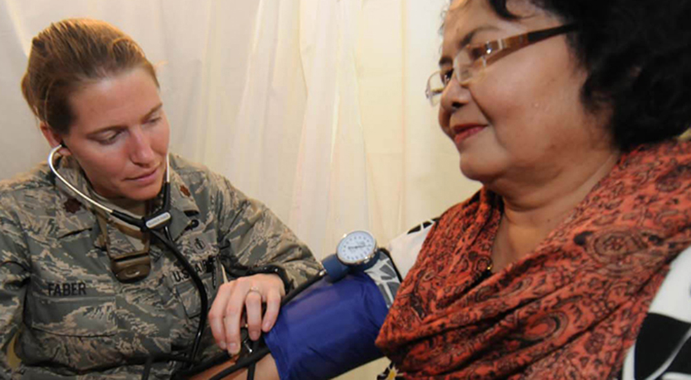 Female Army doctor takes the blood pressure to check a woman's heart health