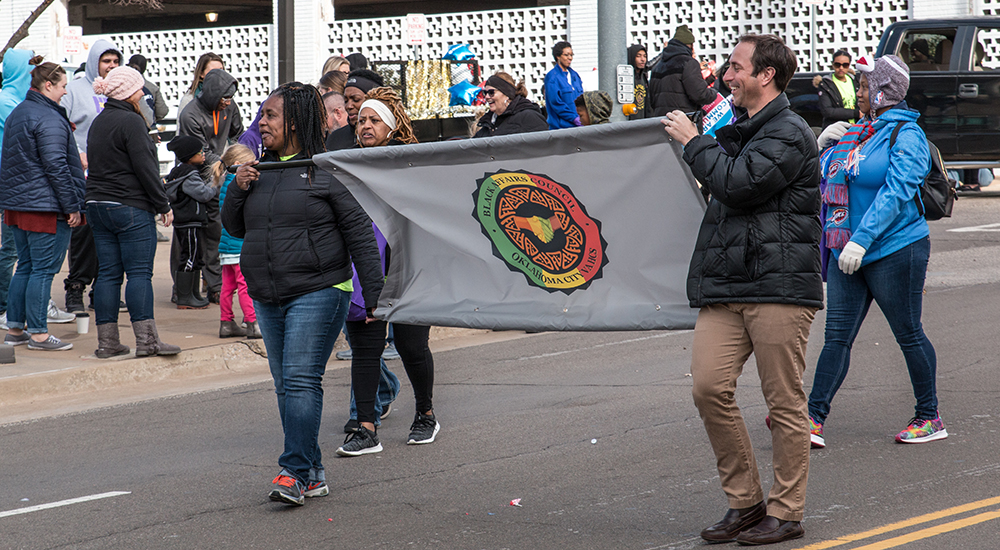 Two people carry a banner in a parade