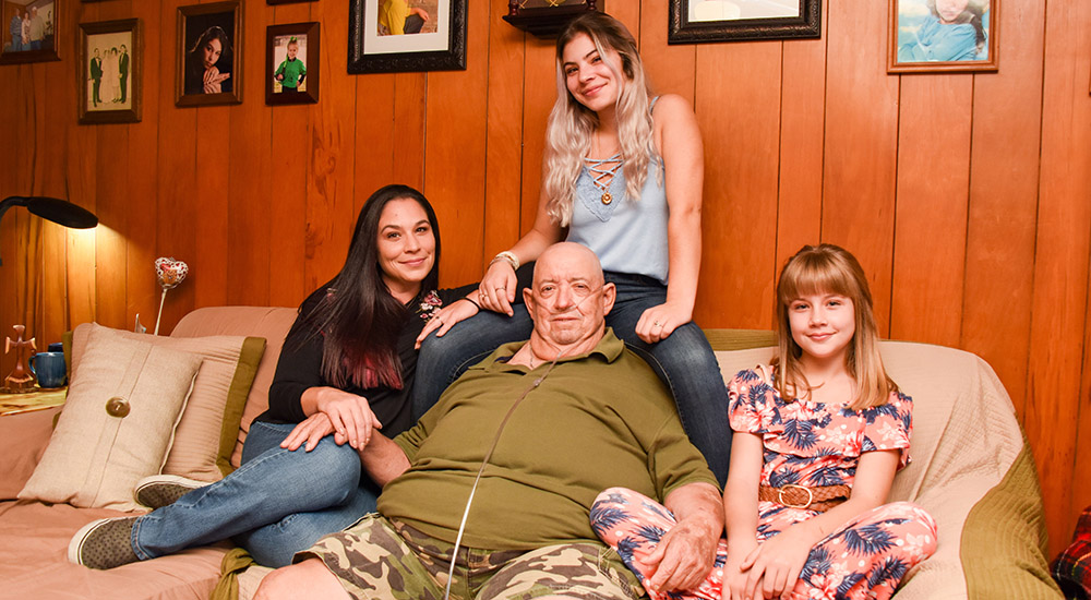 Man sits on a sofa, surrounded by three women