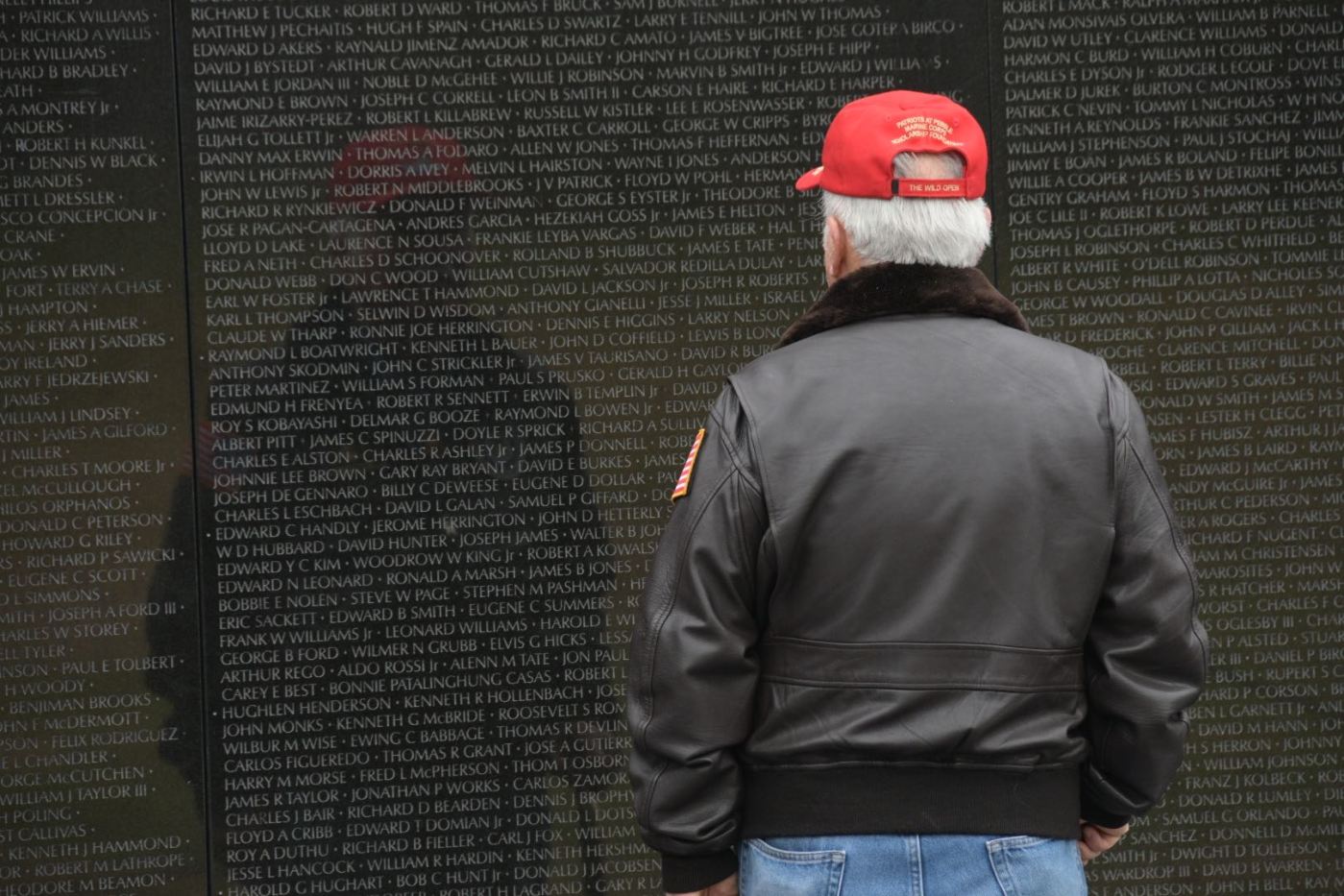 Vietnam Veteran stands in front of Vietnam Memorial Wall.
