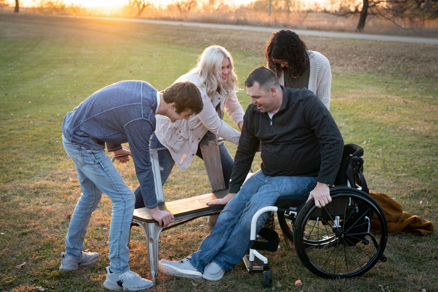 In preparation for a family photo, Army Veteran Jeff Edwards gets help from his girlfriend Dani, and kids Briona and Jakob, to transfer from his wheelchair to a bench.