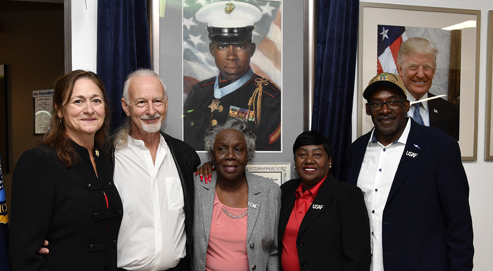 Five people pose in front of new painting of Marine Veteran