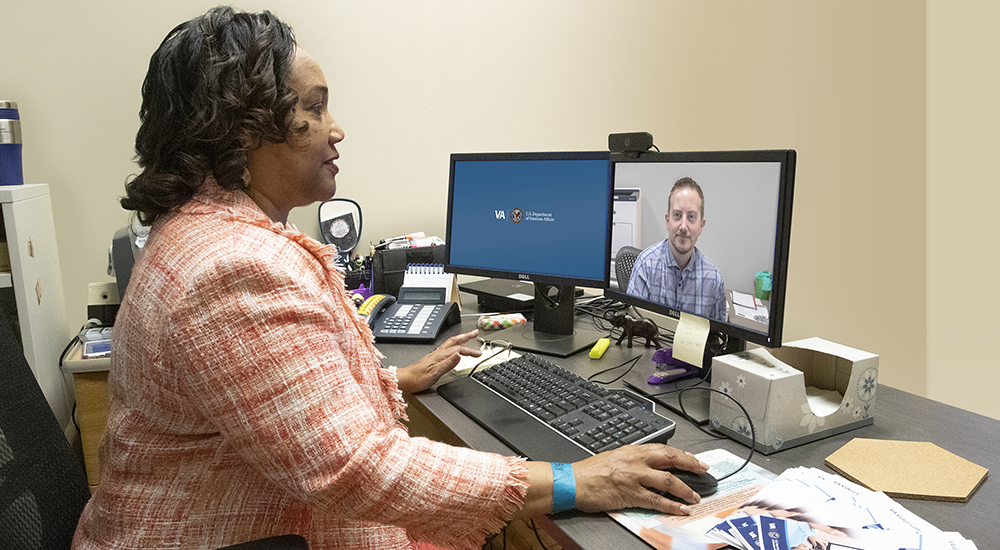 A woman conducts a virtual appointment with man on her computer screen