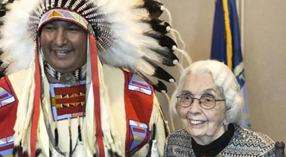 A native American chief in full headdress and a senior woman