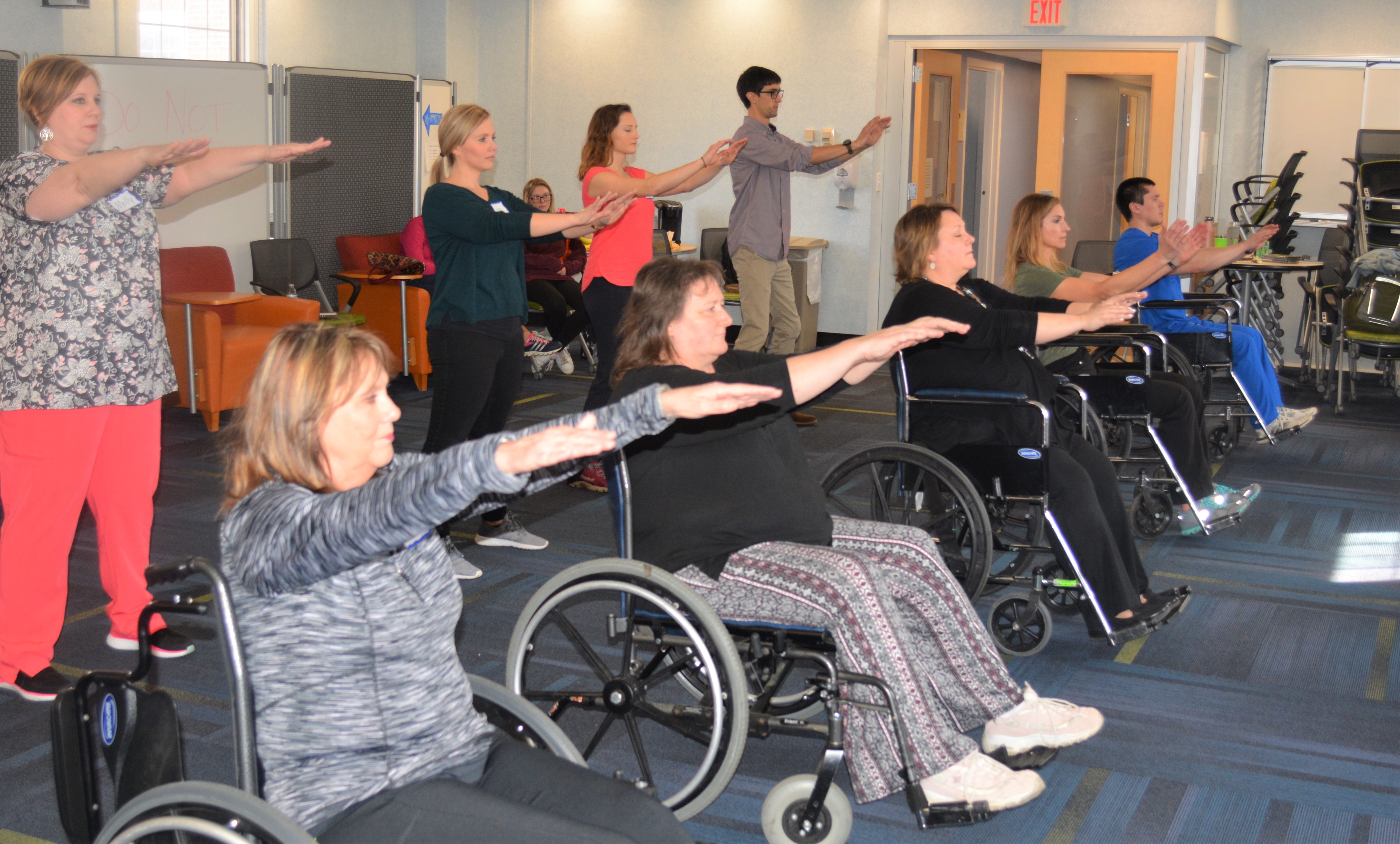 Ten people practice Tai Chi standing and sitting in wheelchairs
