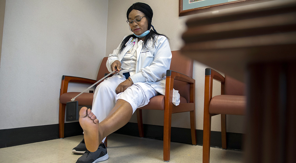 Nurse who specializes in diabetic foot care looking at the bottom of her feet with a mirror