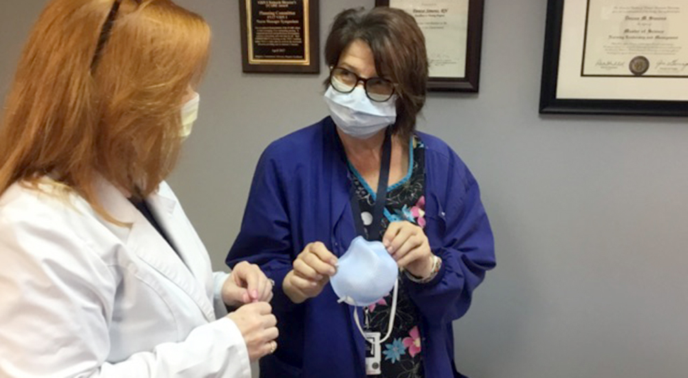 Nurse demonstrates face mask to another nurse