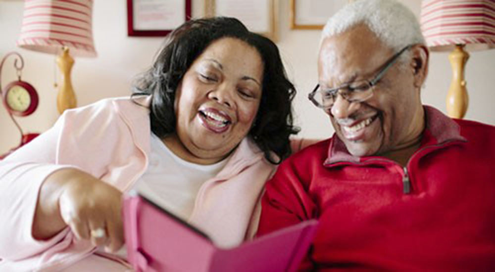 Geriatric man and woman reading and smiling