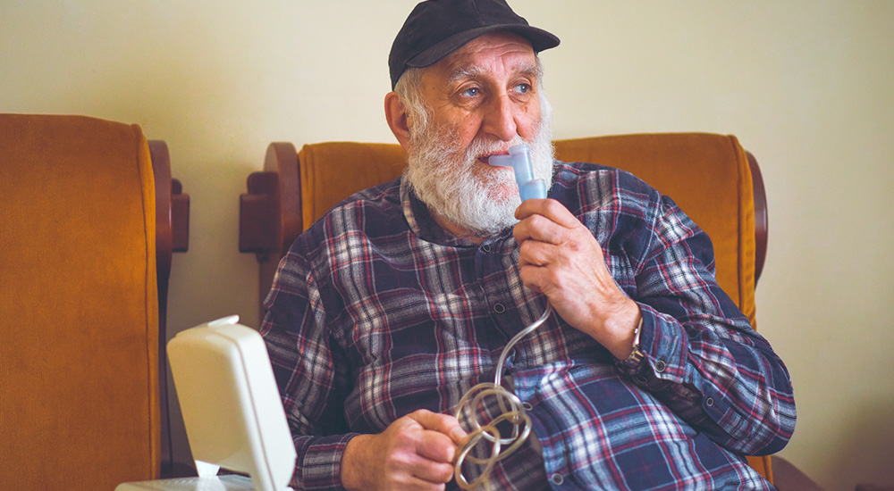 Elderly patient using an oxygen inhaler to assist his lung function