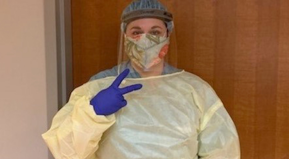 Nurse in PPE gives the victory sign