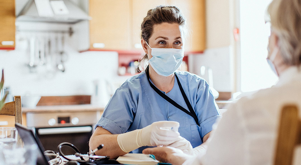 Nurse wearing mask talking to patient