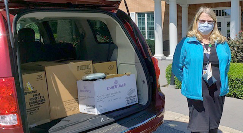 Woman standing next to car loaded with boxes