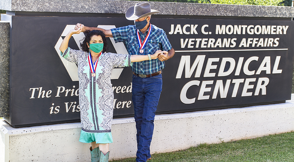 Man and woman dancing in front of VA medical center sign