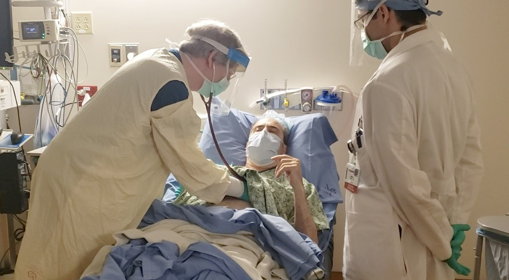 Doctors examine patient in hospital room following transplant