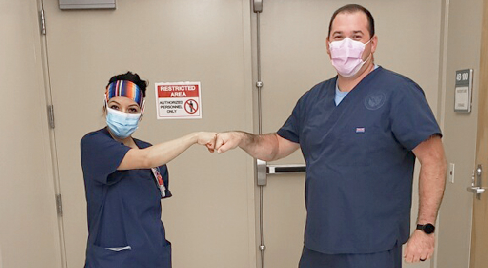 Two nurses in masks fist bump