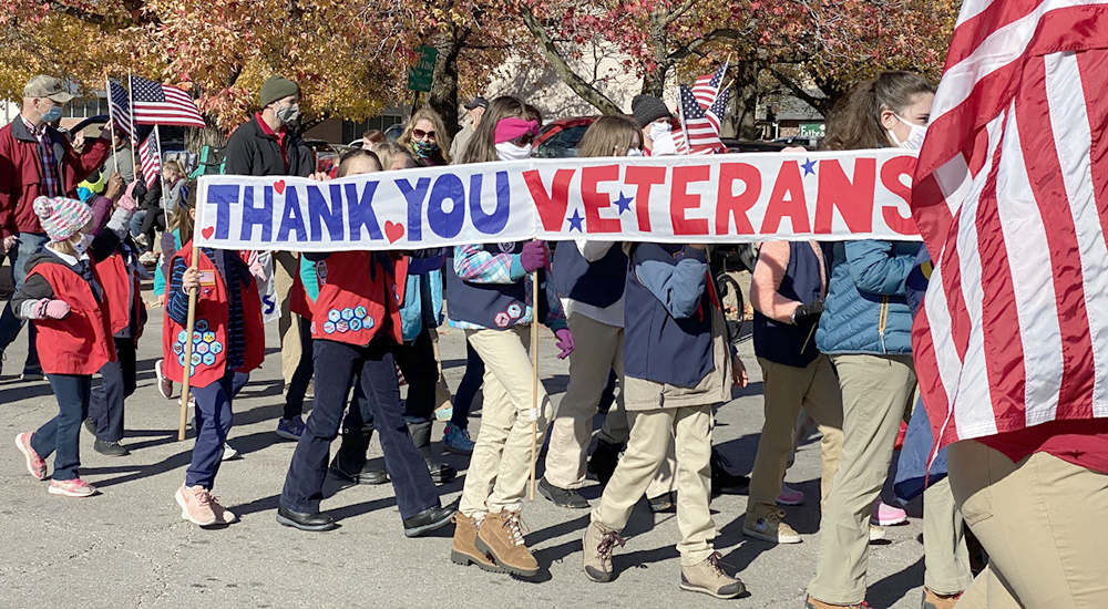 People carrying Thank You Veterans banner in parade