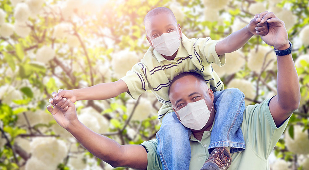 African American Father And Son Playing Outdoors Wearing Medical Face Mask.
