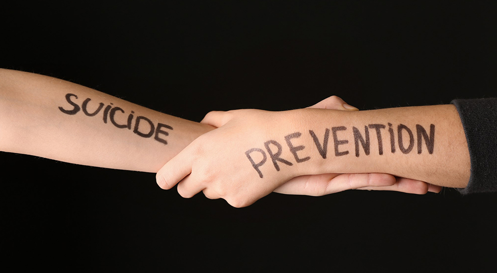 Female hands with text SUICIDE PREVENTION on dark background