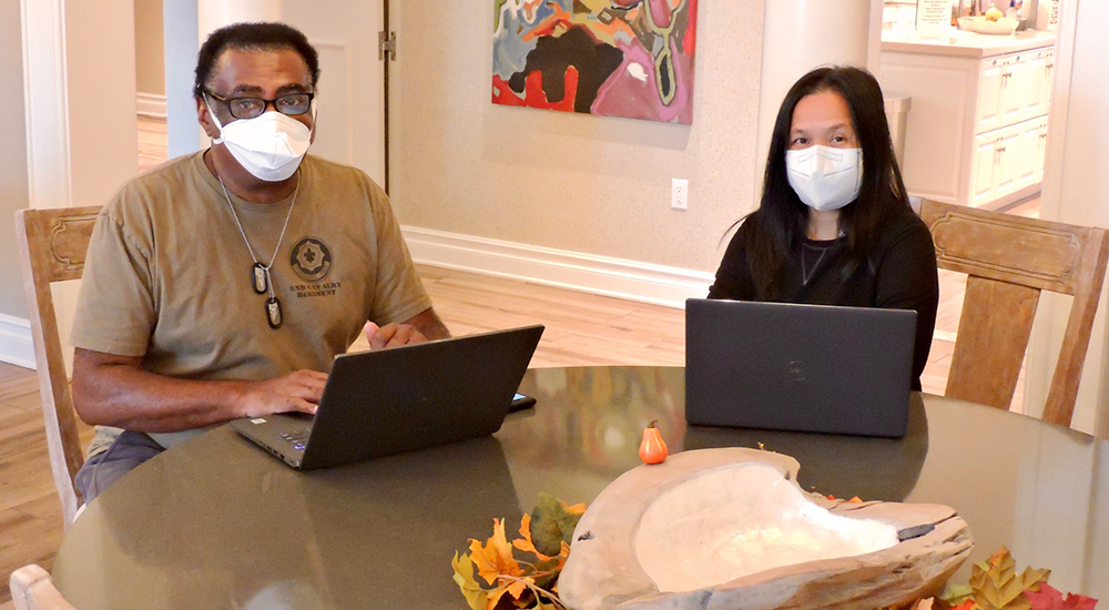 Man and woman wearing masks working on laptops