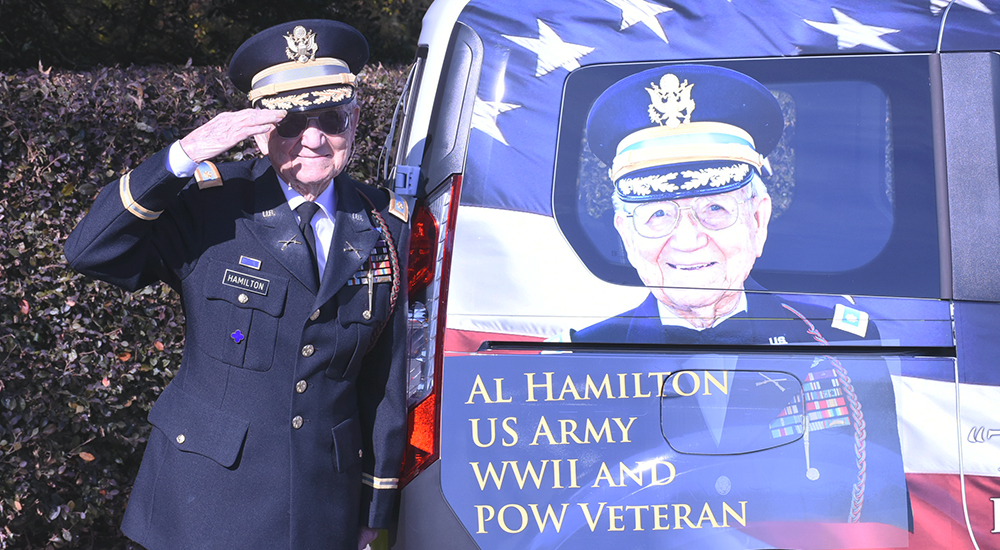 Elderly Army Veteran salutes next to a van with his image painted on it