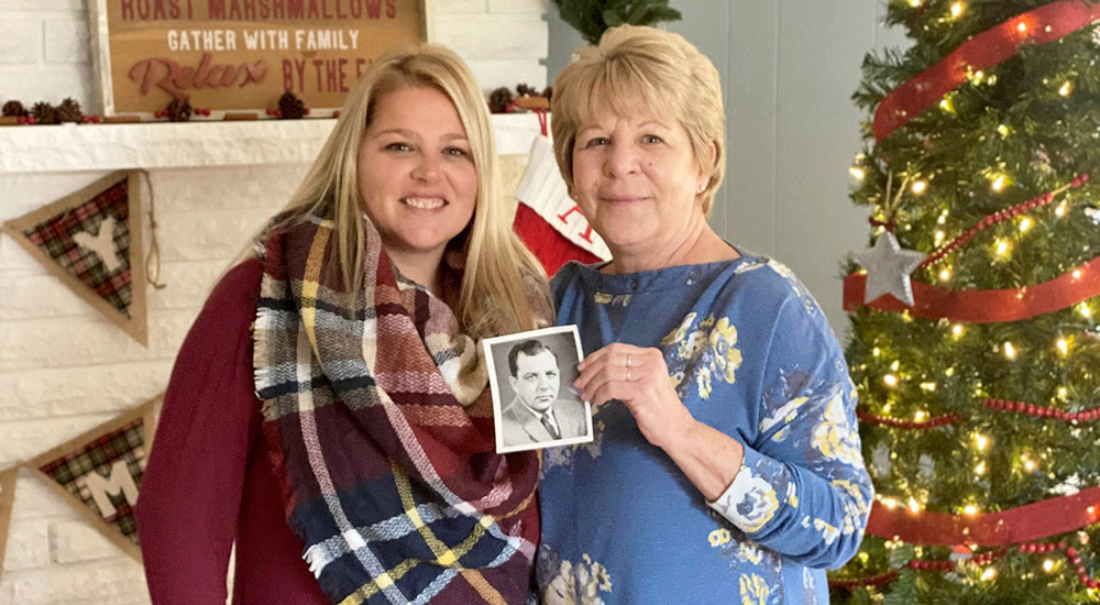 Pam Lajoie stands with her daughter, Shannon Cochran while holding a photograph of her father, Art Middleton. Both carry on their father's legacy of caring for Veterans as VA staff members in Battle Creek.