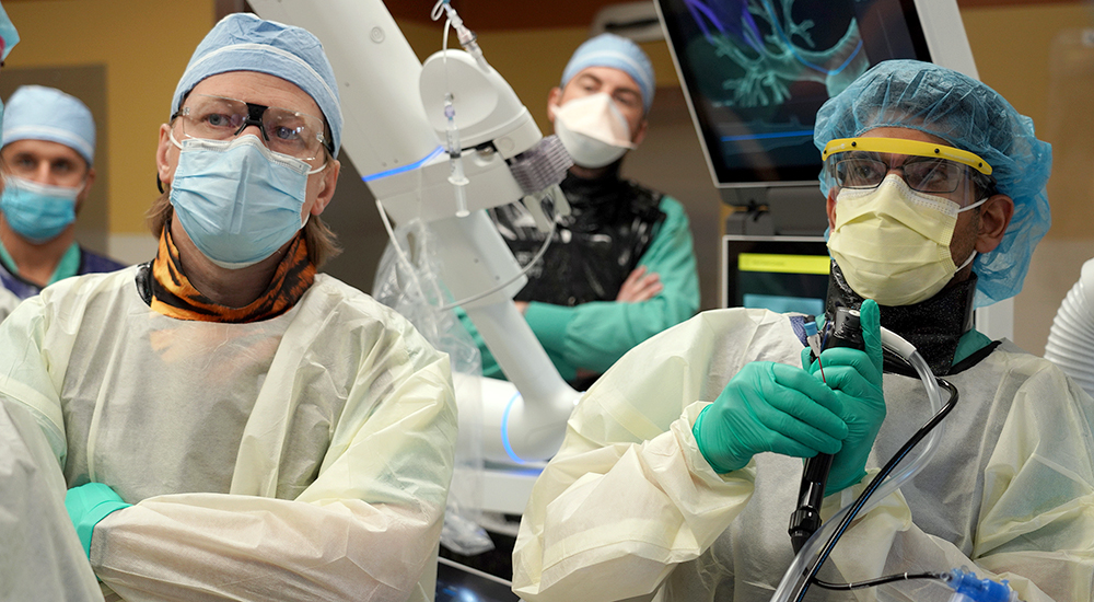 Doctor operates robotic system as others observe