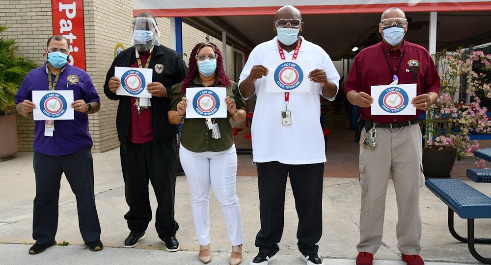 Five people wearing masks holding up signs