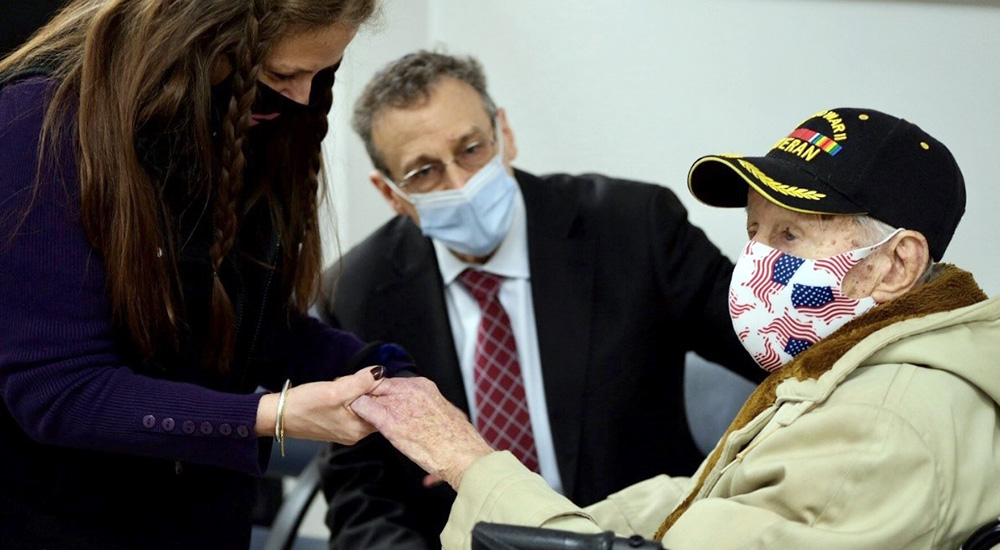 Woman holds hand of elderly Veteran in wheelchair