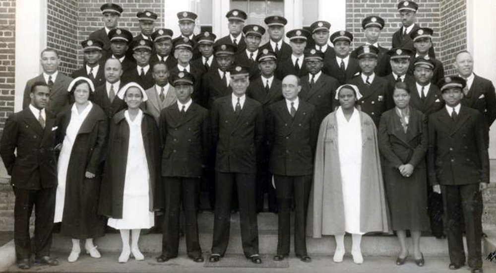 Large group in uniforms and nurses capes on door steps
