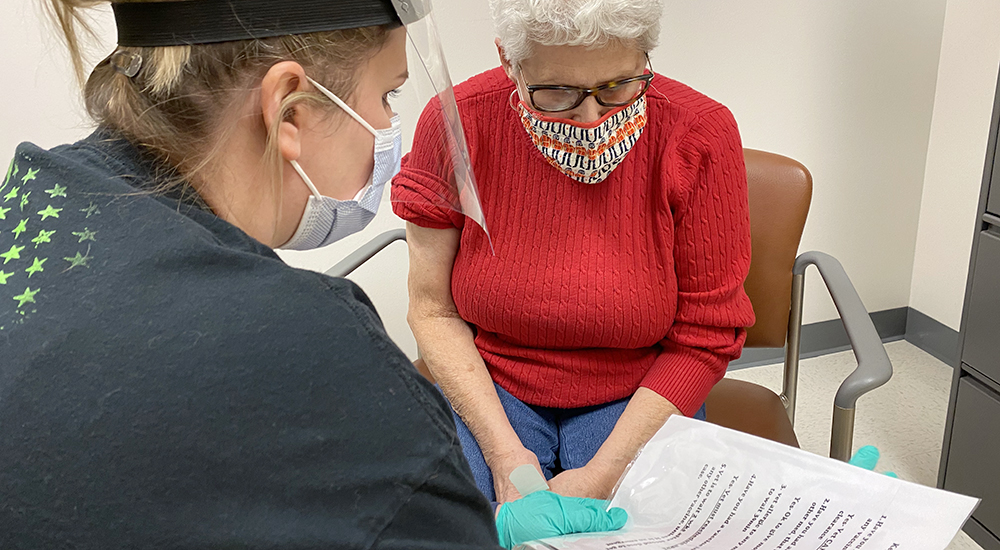 Nurse and female Veteran read vaccine information