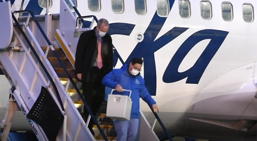 Man carrying vaccines down airplane stairs