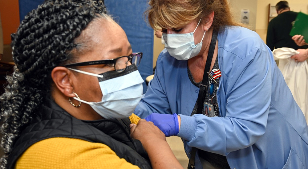 A health care worker gives an injection to a woman patient