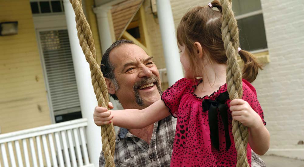 Man and his daughter who is in a swing