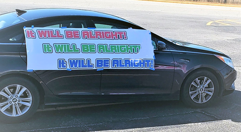 Car with IT WILL BE ALL RIGHT sign