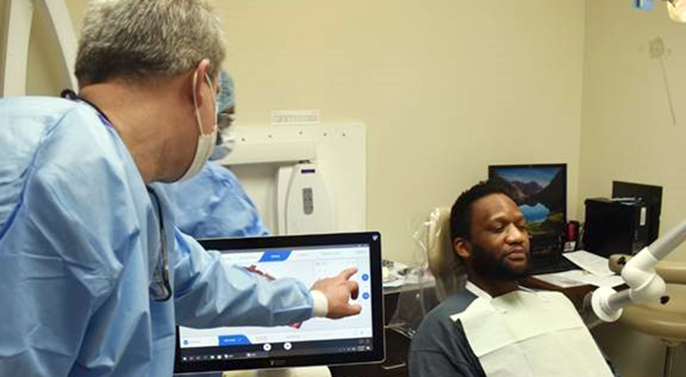 Dentist indicating dental process on computer screen