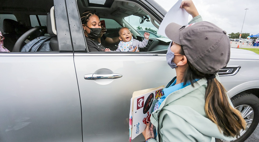Woman holding up sign for smiling baby in car
