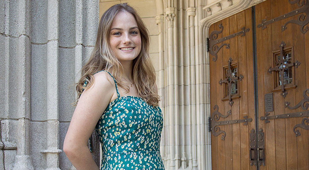 Photo of smiling young woman at university door