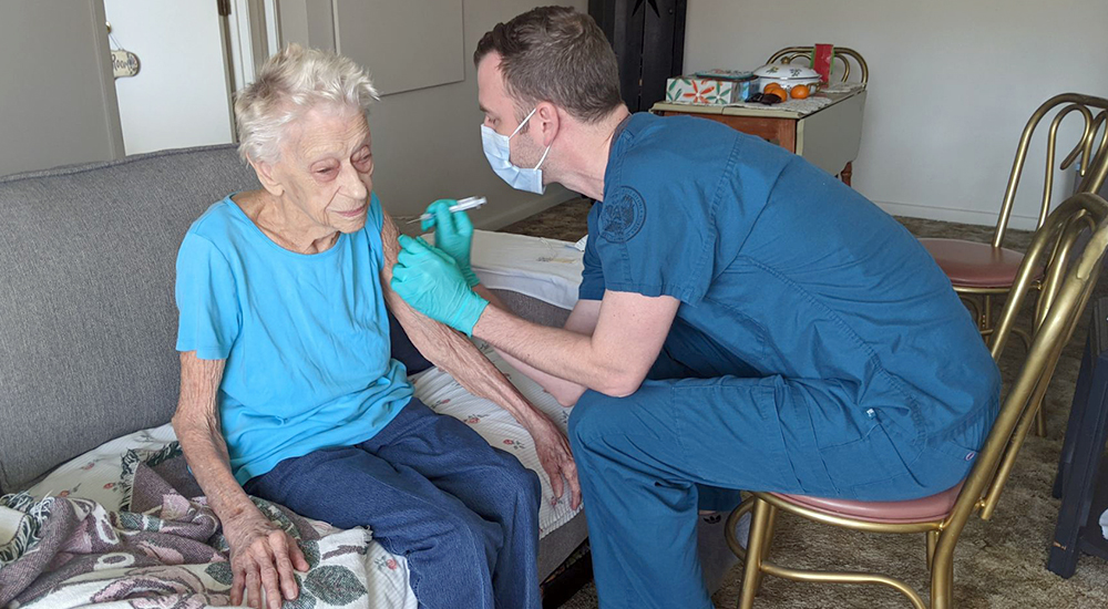 A pharmacist vaccinates an elderly woman