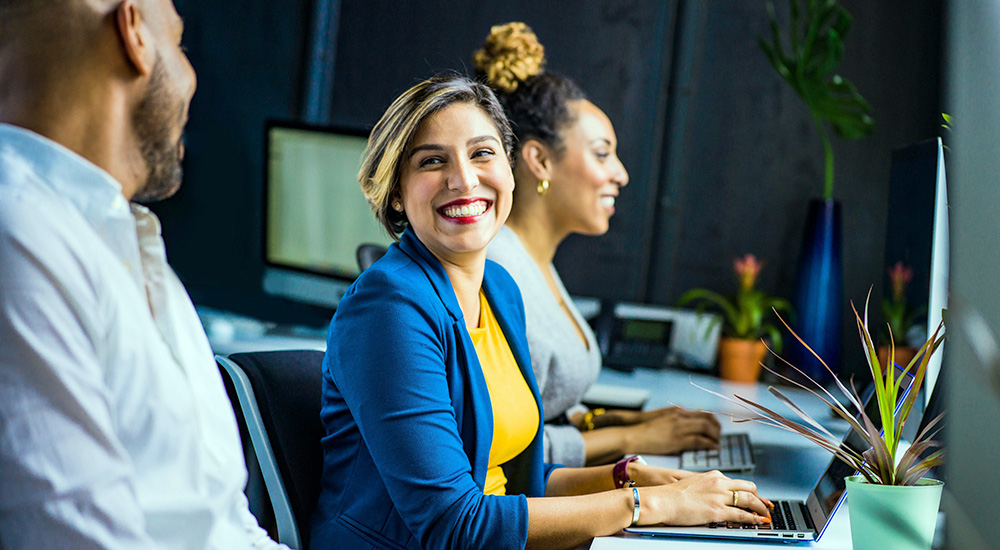 Three smiling employees at workstations