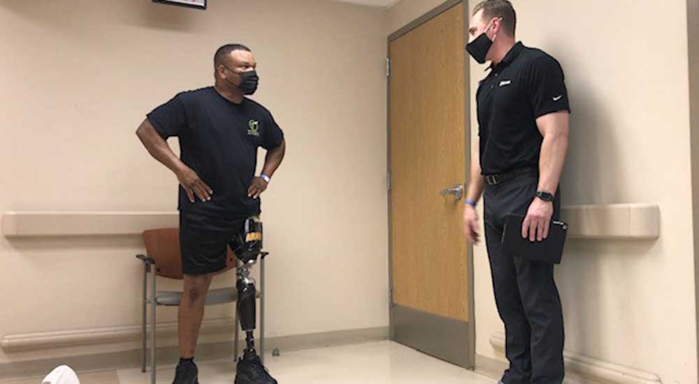 Man with prosthetic leg talks with trainer