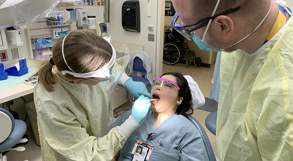 Doctor examines an employee's mouth while another doctor looks on