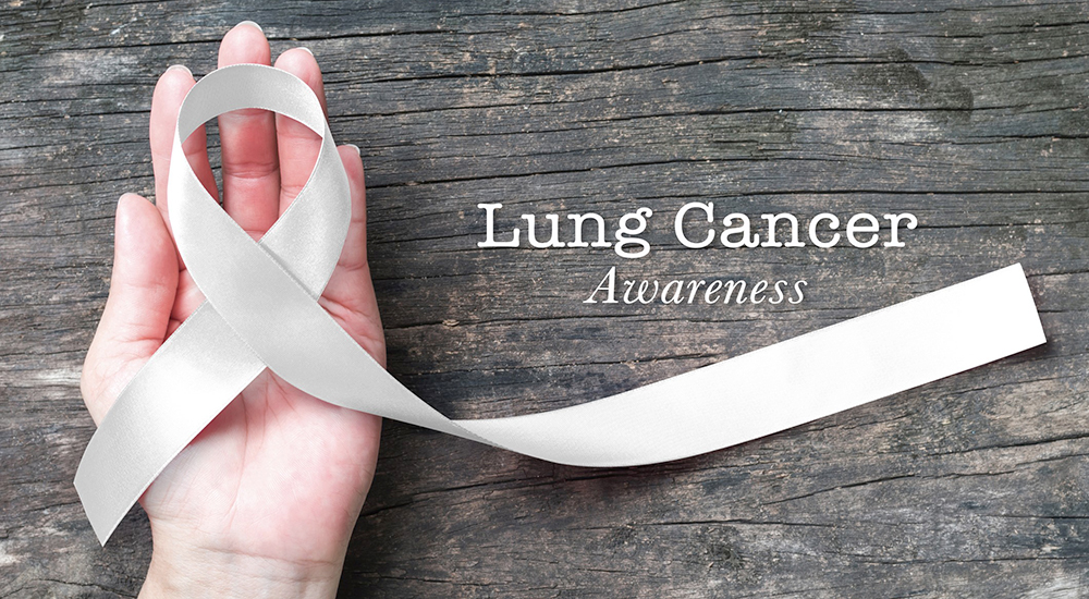 Lung cancer awareness month with white/ light pearl color ribbon on woman's hand support on aged wood
