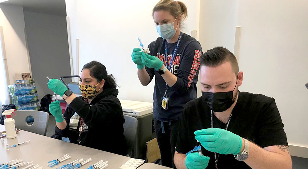 Three clinical staff members prepare vaccines
