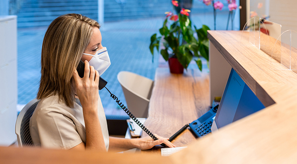 Woman wearing mask on the phone in workstation.