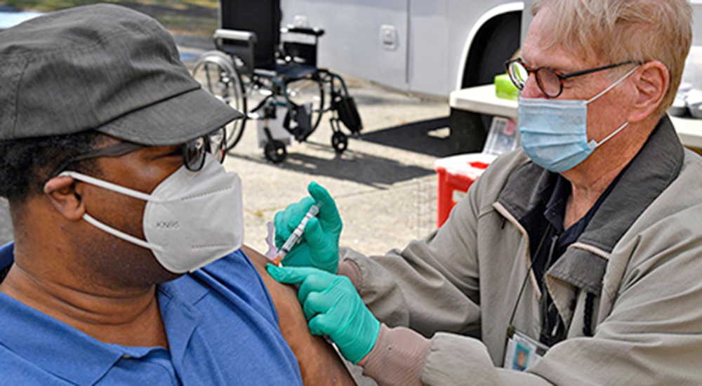 A male nurse vaccinates a man