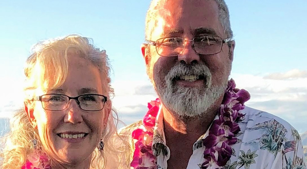 Man and wife in Hawaiian shirts and wearing leis