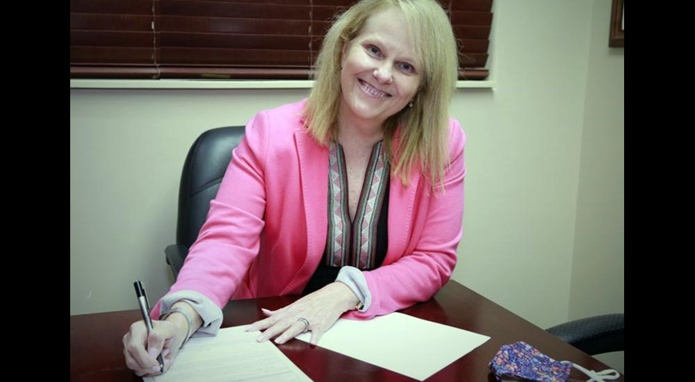 Smiling woman in pink jacket signing papers