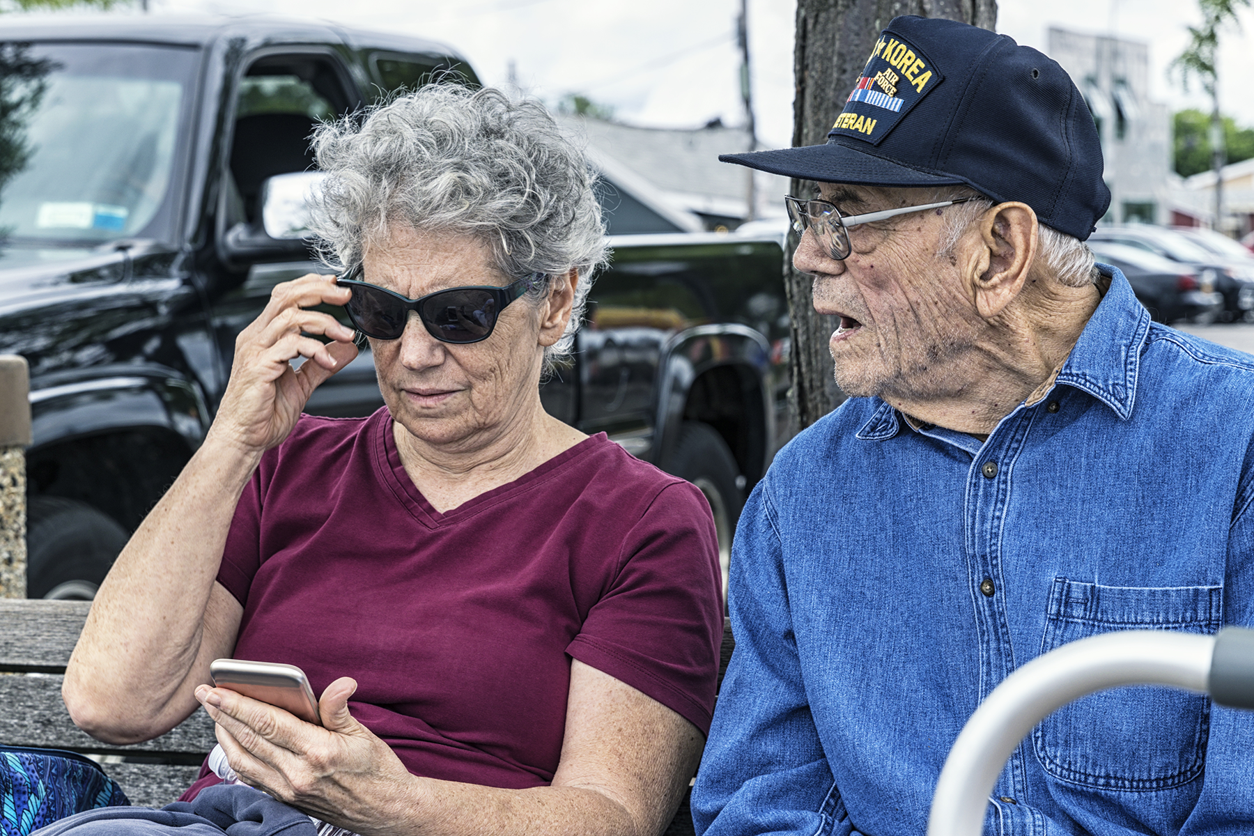 An elderly Veteran sits with his caregiver daughter as they review her phone